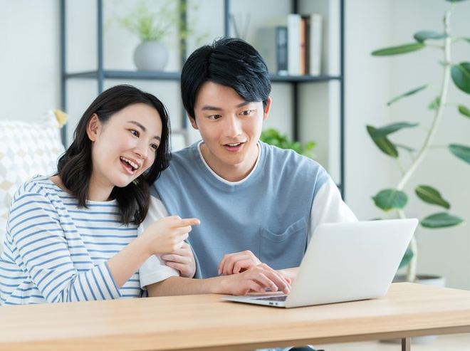 リビングでパソコンを見ながらオンライン相談する夫婦
